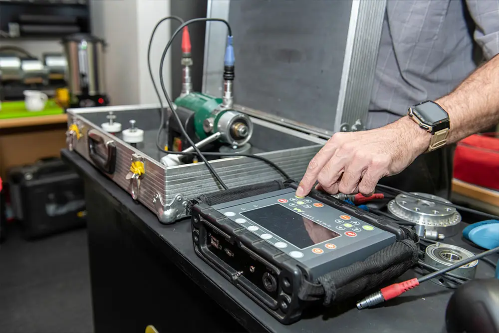 "Technician using ultrasonic flaw detector with probe on metal specimen during nondestructive testing"