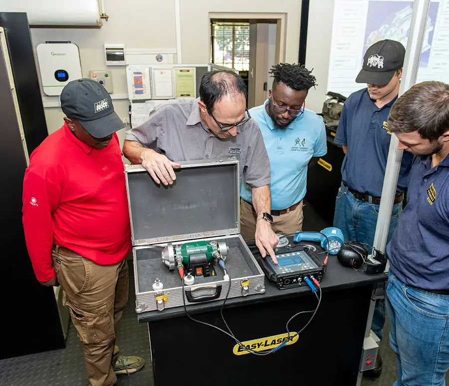Five people observe equipment demonstration with measuring instruments labeled “EASY-LASER.”