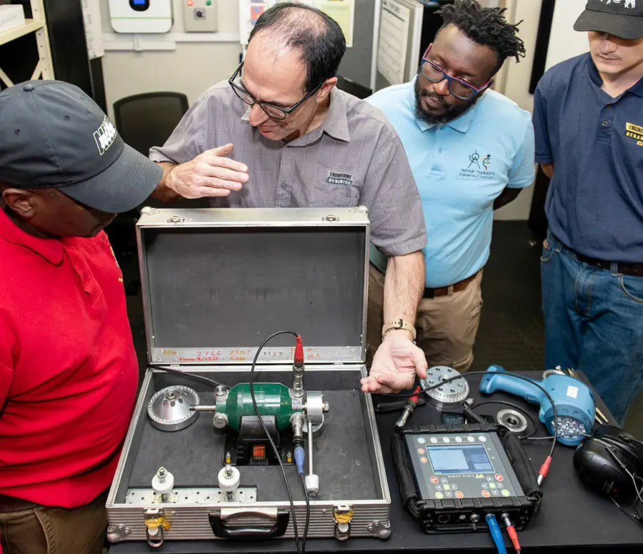 "Group of engineers discussing calibration equipment with digital measurement device on table