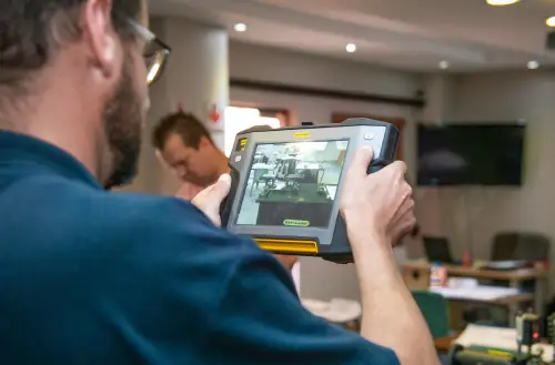 “Technician using handheld thermal imaging device in workshop”